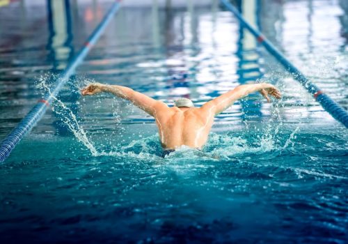 male-swimmer-performing-the-butterfly-stroke-at-indoor-swimming-competition.jpg
